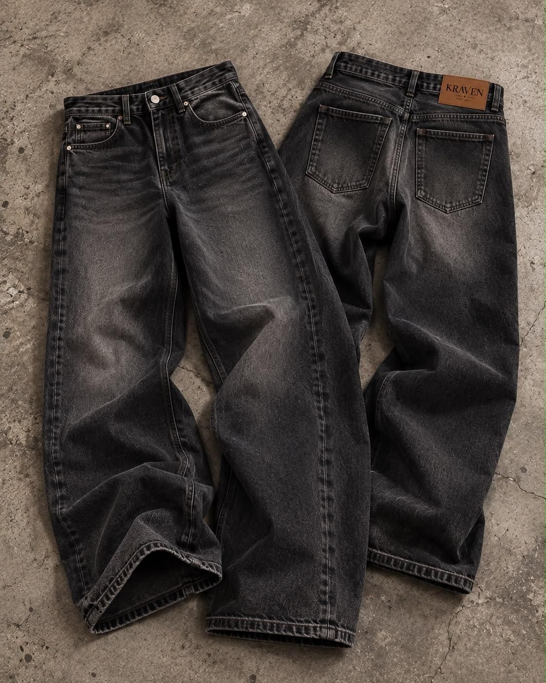 Krav'en Wide-Leg Denim in Washed Black, front and back, laid flat on concrete, with the leather Krav'en patch on the back waistband.