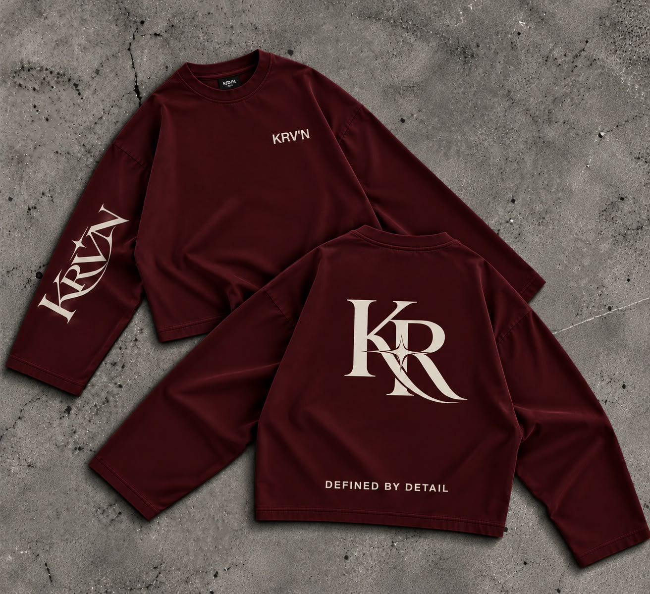 Krav'en KR Jumper in Burgundy, front and back, laid flat on concrete: the KR monogram in cream across the back, KRV'N in script down the sleeve.
