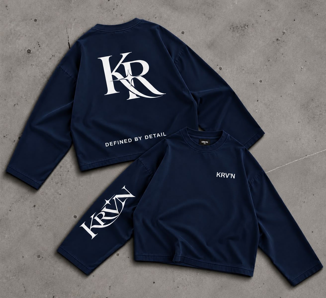Krav'en KR Jumper in Navy, front and back, laid flat on concrete: the KR monogram in white across the back, KRV'N in script down the sleeve.