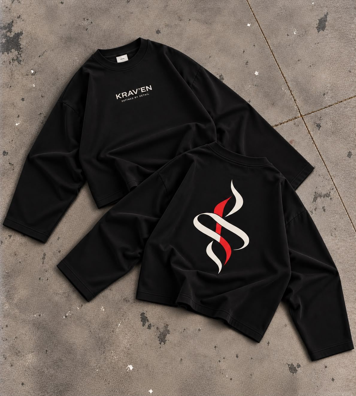 Krav'en Monogram Jumper in Black and Red, front and back, laid flat on concrete: the ribbon monogram in bone and red across the back, the wordmark on the chest.