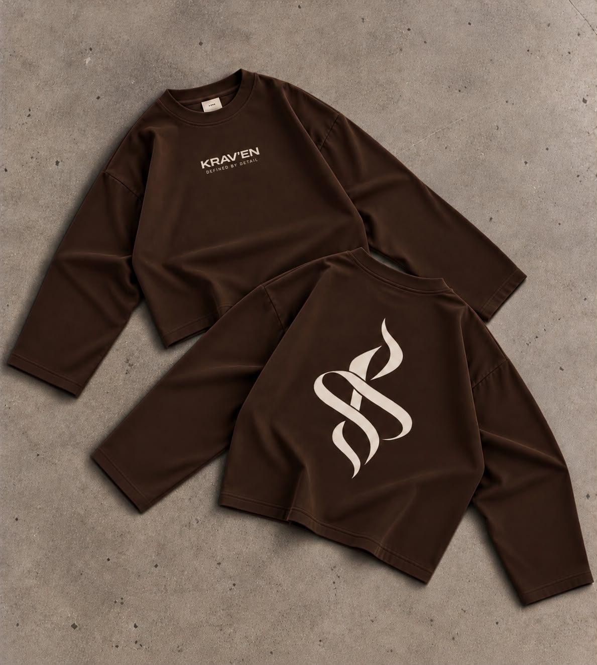 Krav'en Monogram Jumper in Chocolate, front and back, laid flat on concrete: the ribbon monogram in bone across the back, the wordmark on the chest.